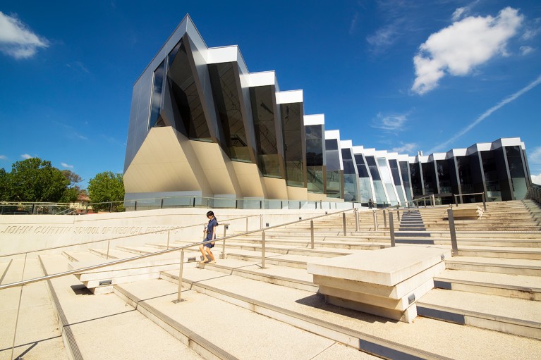 Person walking down steps in front of a modern building