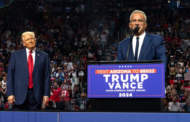 Un anciano de cabello amarillo, un ala azul y una corbata roja a la izquierda, y un hombre de cabello blanco con un ala azul hablan desde el podio durante un mitin. El ex candidato presidencial Robert F. Kennedy Jr. (R) habla mientras el candidato presidencial republicano El ex presidente estadounidense Donald Trump escucha durante un mitin de campaña en el Desert Diamond Arena el 23 de agosto de 2024 en Glendale, Arizona.