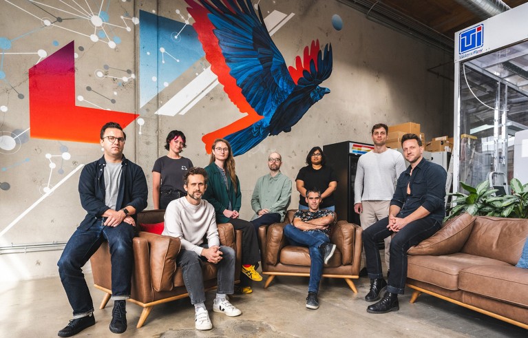 Group of scientists standing and sitting posing in the FutureHouse office with a bird drawing on the wall. The team is behind PaperQA and WikiCrow AI tools..