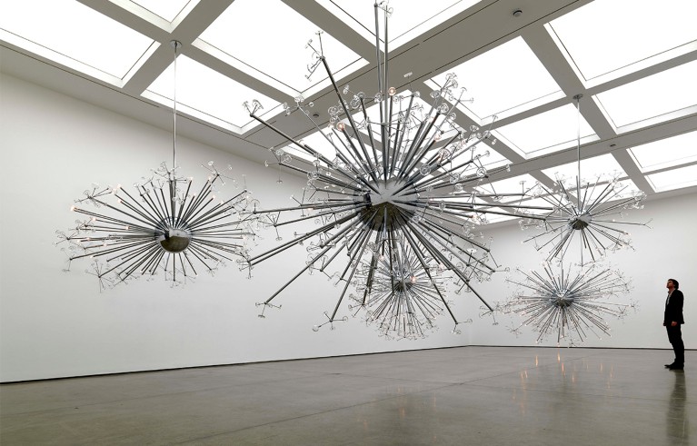 A man stands before a large sculpture star shaped, admiring the artwork in a museum setting.