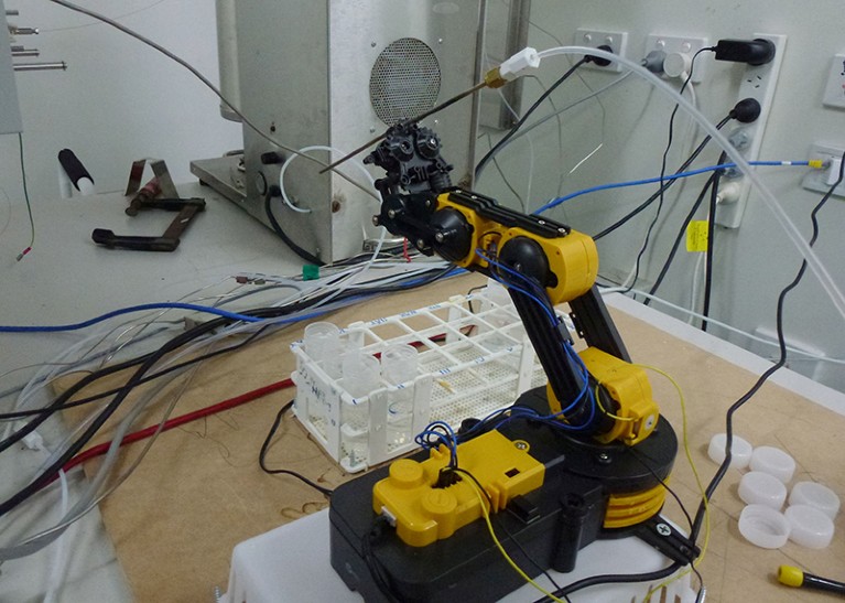 A yellow plastic robotic arm is seen on a desk