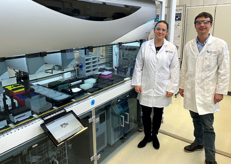 Julia Tenhaef (left) and Stephan Noack (right) stand in front of the “AutoBioTech” platform in their lab