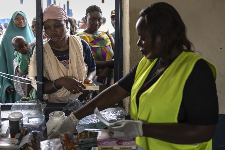 A health worker gives medicine to a woman at a shelter for internally displaced persons from floods, in Lokoja, Nigeria.