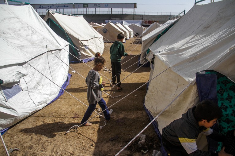 Children walk between tents set up in the al-Yarmouk neighborhood for displaced persons, in Gaza City.