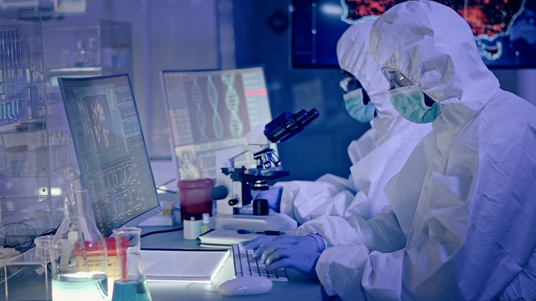 A team of people in PPE work with a microscope and computers to understand a virus.