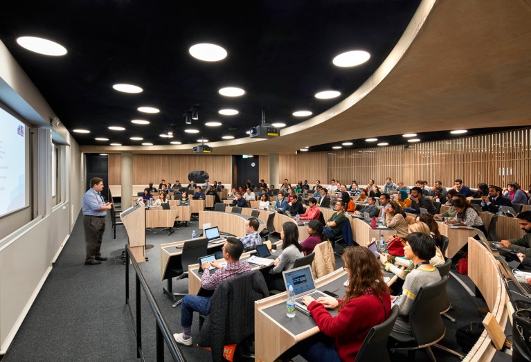 Vista general de un profesor dirigiendo la clase en una sala de conferencias curva