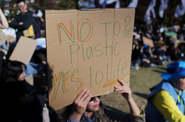 A woman holds up a sign that reads "no to plastic yes to life" during a protest