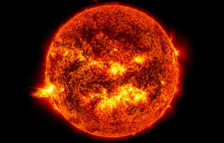 An image showing the bright light of a solar flare on the left side of the sun.