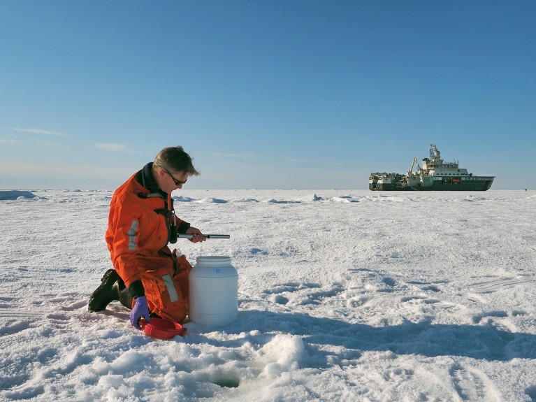 Paul Dodd, taking samples of snow and ice on an ice-station, on a Fram Strait cruise, with the ship in the background.