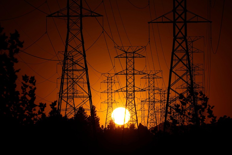 The sun sets behind high tension electric grid power lines.