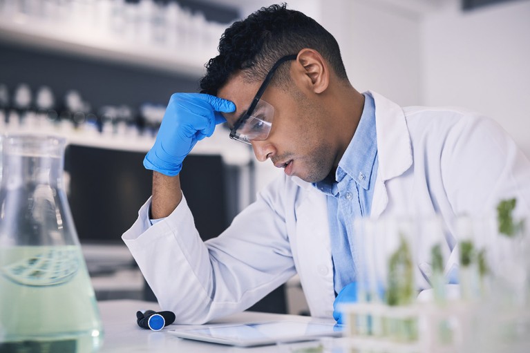 A concerned researcher reviews data on a tablet in a research laboratory.