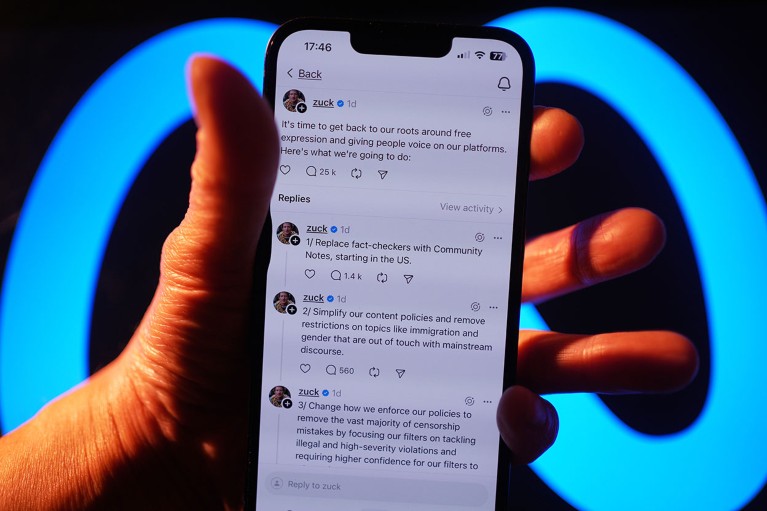 A hand holds a smartphone displaying a series of posts by Meta CEO Mark Zuckerberg announcing Meta fact-checking changes on the Threads social media app.