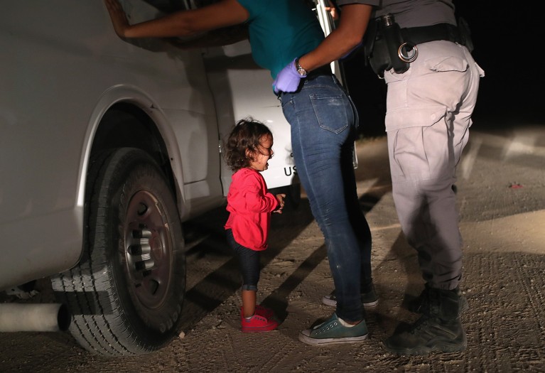 A two-year-old Honduran asylum seeker cries as her mother is searched and detained near the U.S.-Mexico border in 2018.