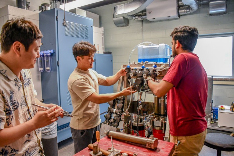 Researchers in a workshop work on a bench-top elastocaloric cooling system prototype