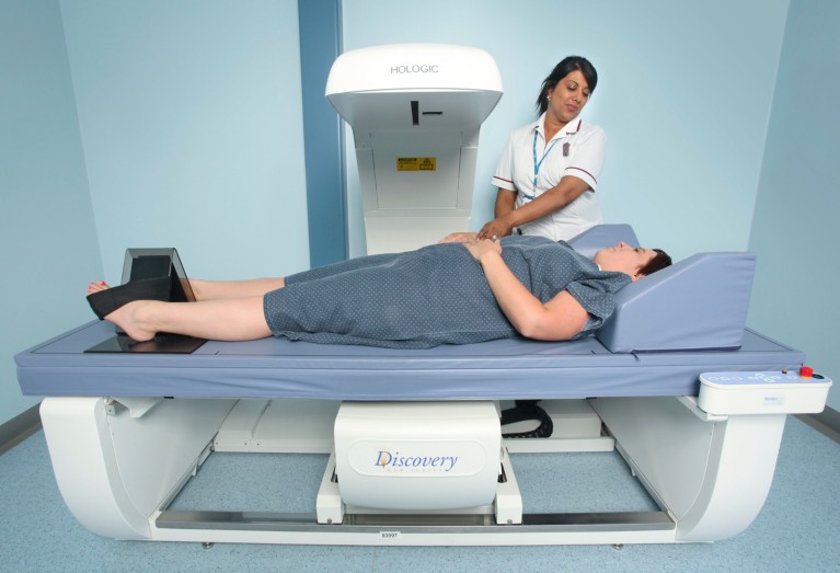 A patient lies down while a hospital radiographer operates a DXA scanner