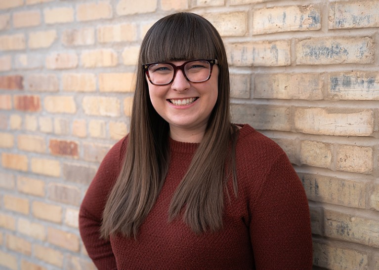 A portrait of Nicole Bedera standing in front of a wall.