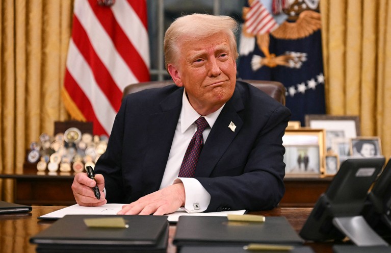 U.S. President Donald Trump signs executive orders in the Oval Office of the White House on January 20, 2025.