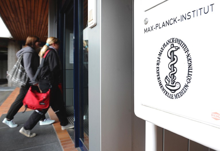 A sign for the Max Planck Institute for Experimental Medicine is seen in the foreground as students enter the building in the background