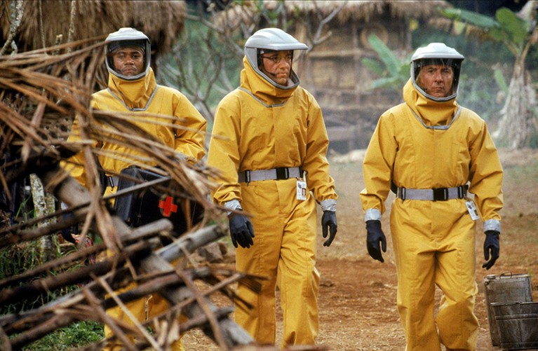 A film still from the film Outbreak showing three men in yellow hazmat suits walking together