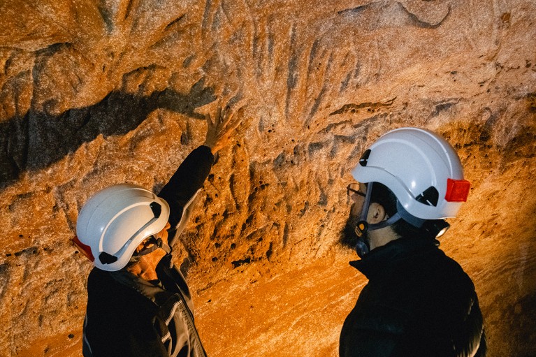 Juliano Campos looks at the claw marks in the cave in Brazil, while standing next to the guide.