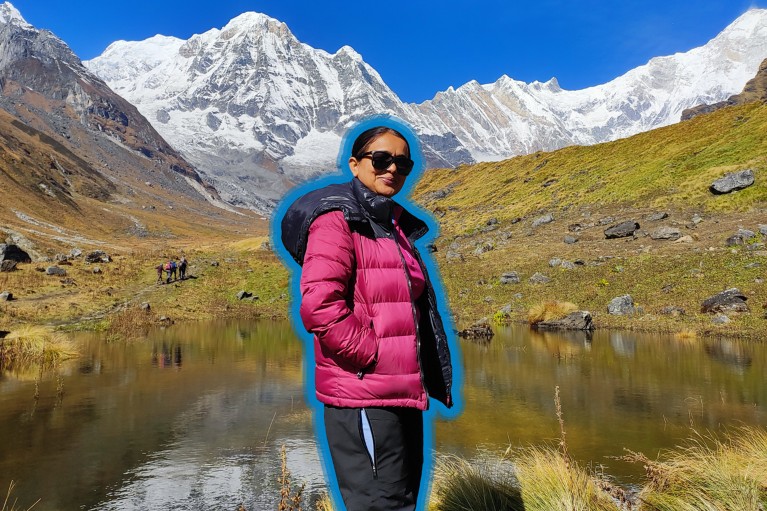 Babita Paudel, evidenziata da un contorno blu, si trova di fronte a una montagna innevata in una giornata di sole