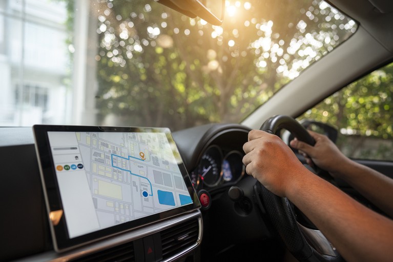 Person driving a car with a GPS navigation tablet on.