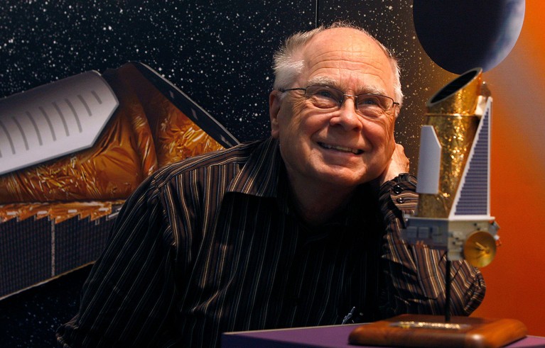 Portrait close up of William Borucki in front of a mini telescope model.