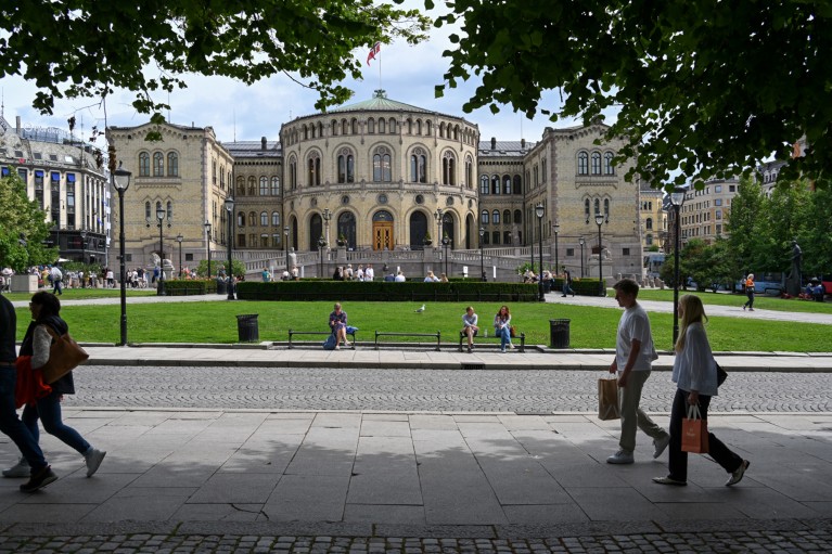 I pedoni passano oltre l'edificio del Parlamento norvegese di Oslo