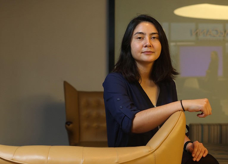 Erika Cheung sits with her hand on the back of a chair