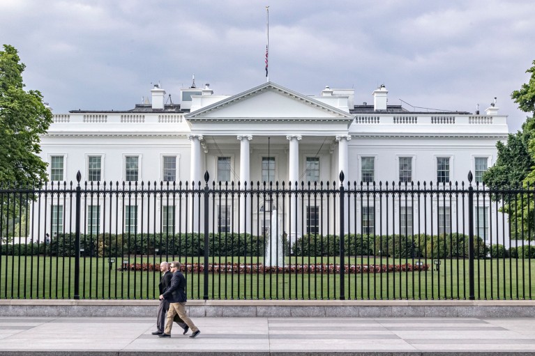 Exterior view of the northern side of the White House, with police officers patrolling outside the black fencing