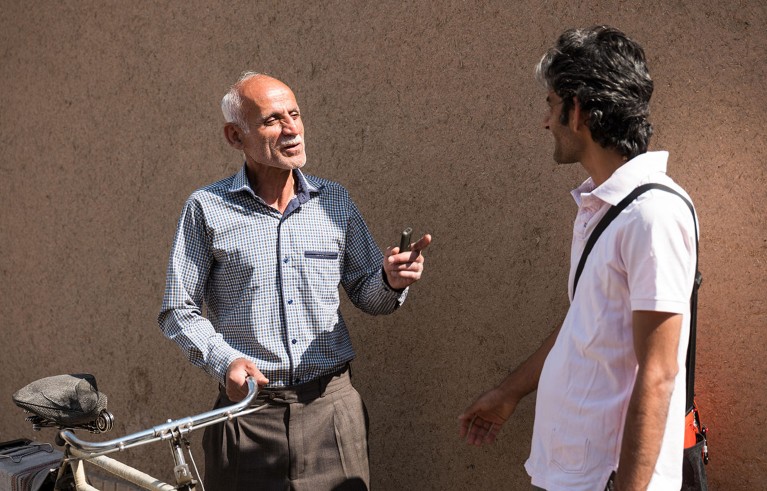 Two Iranian man on the street in Kashan, Iran, telling jokes and laughing.