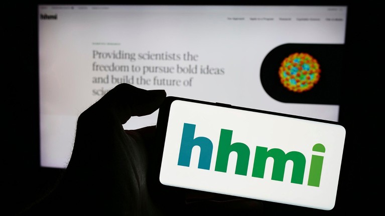 Person holding a cellphone with the logo of Howard Hughes Medical Institute (HHMI) in front of their webpage.