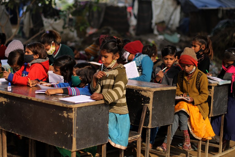 Children wearing face masks study at desks at an outdoor classroom