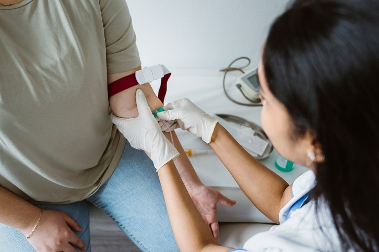 High angle view of a doctor taking a blood sample from a patient's left arm.