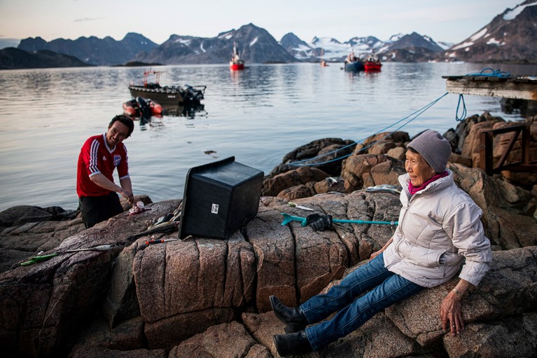 People gather to clean fishes on the shoreline in Kulusuk (also spelled Qulusuk), a settlement in the Sermersooq municipality on the southeastern shore of Greenland.