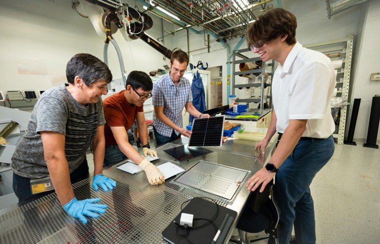 The Sunflex Solar engineering team standing around a lab bench looking at a thin square aluminium electrode