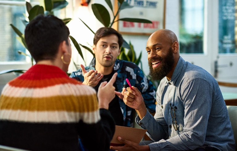 A group of three people gesturing during a conversation.