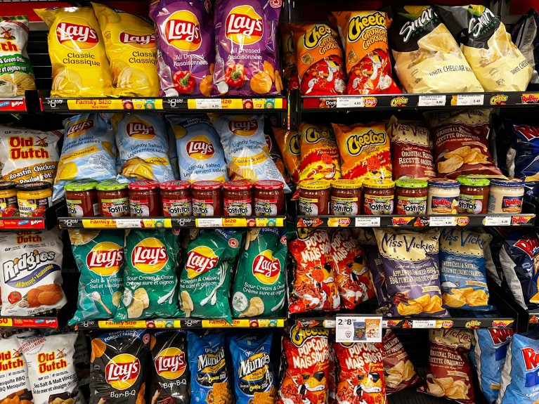 Rows of colourful packets of Lay's and Cheetos crisps are seen on a supermarket shelf