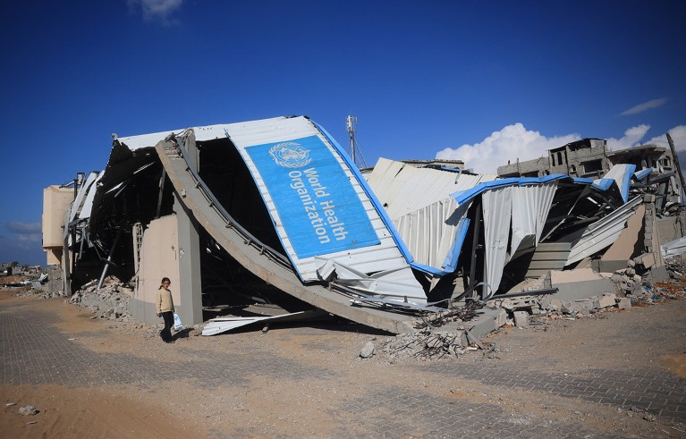 A Palestinian girl walks past a damaged World Health Organisation storage centre hit in recent Israeli bombardment in Khan Yunis in the southern Gaza Strip.