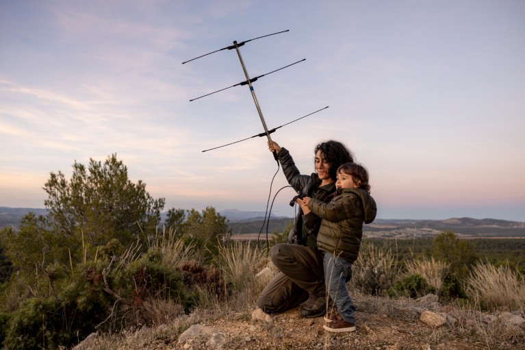 Mariola Sanchez Cerdà e la sua giovane figlia tengono una grande antenna radiofonica mentre si trova in cima a una cima in una catena montuosa nel sud della Spagna