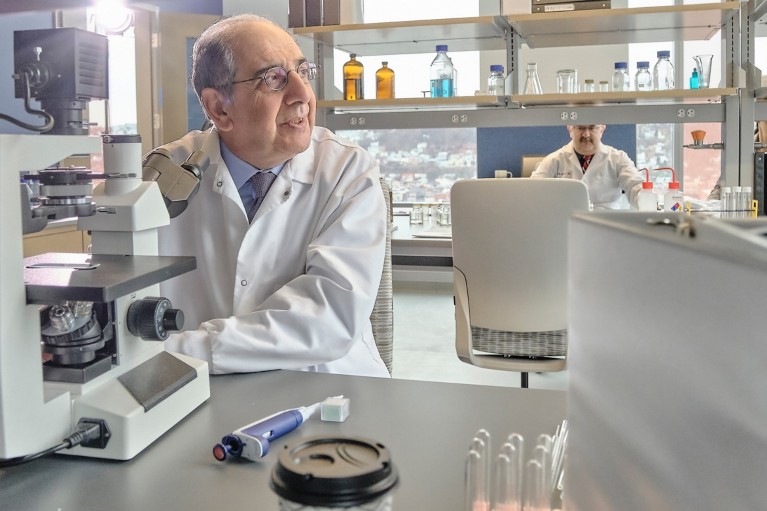 José-Alain Sahel sits at a microscope in a lab