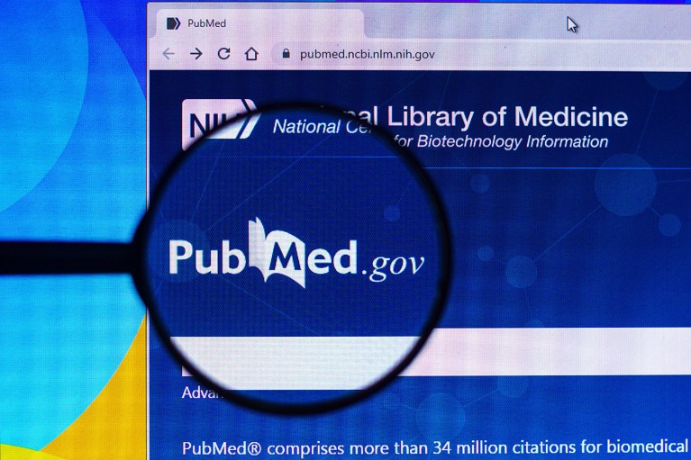 The PubMed website displayed on a computer screen with the PubMed logo highlighted by a magnifying glass.