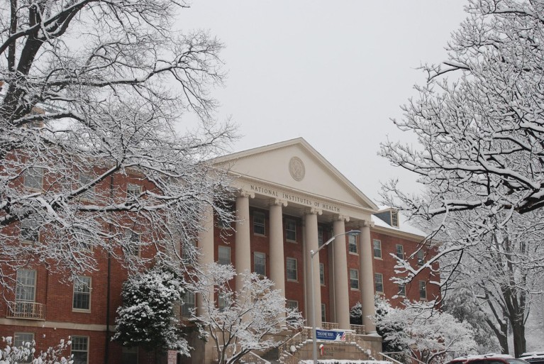 The National Institutes of Health Building exterior in winter with snow on trees.