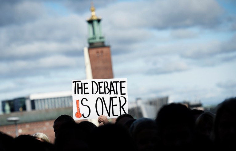 People hold a sign saying the debate is over during a protest out of the United Nations building.