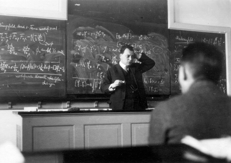 Wolfgang Pauli delivering a lecture with formulas written on a chalkboard, in Copenhagen, 1929.