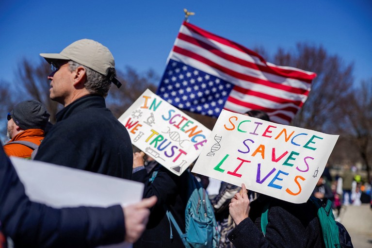 Demonstrators hold signs and an upside-down U.S. flag during a "Stand Up for Science" rally.