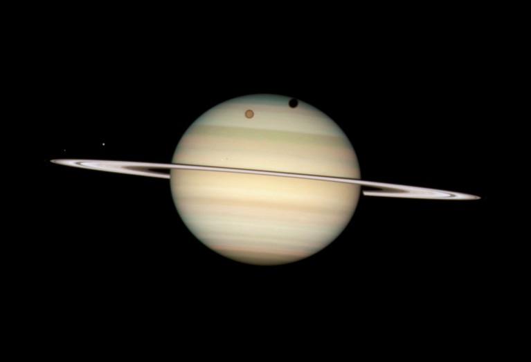 A colour Hubble Space Telescope image of Saturn, showing its rings and a few moons dotted around it.