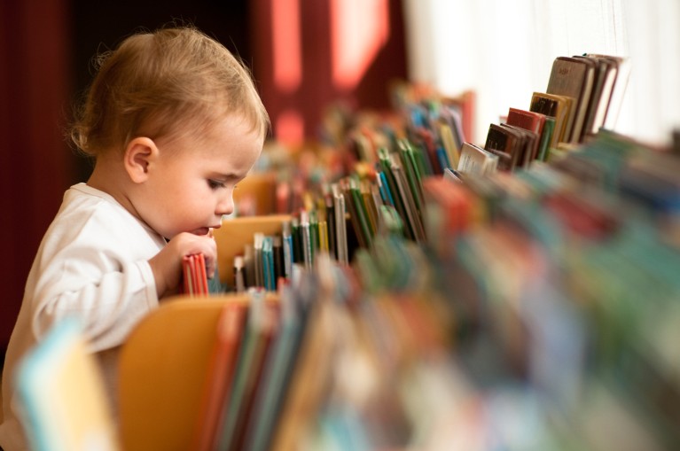 A toddler looking through a colourful display of books in a library