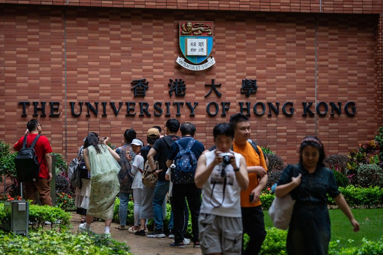 A crowd of people taking photos beneath the University of Hong Kong sign in Hong Kong.