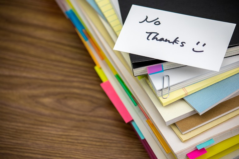 A post it note with the words "no thanks" written on it is stuck on top of a pile of paperwork